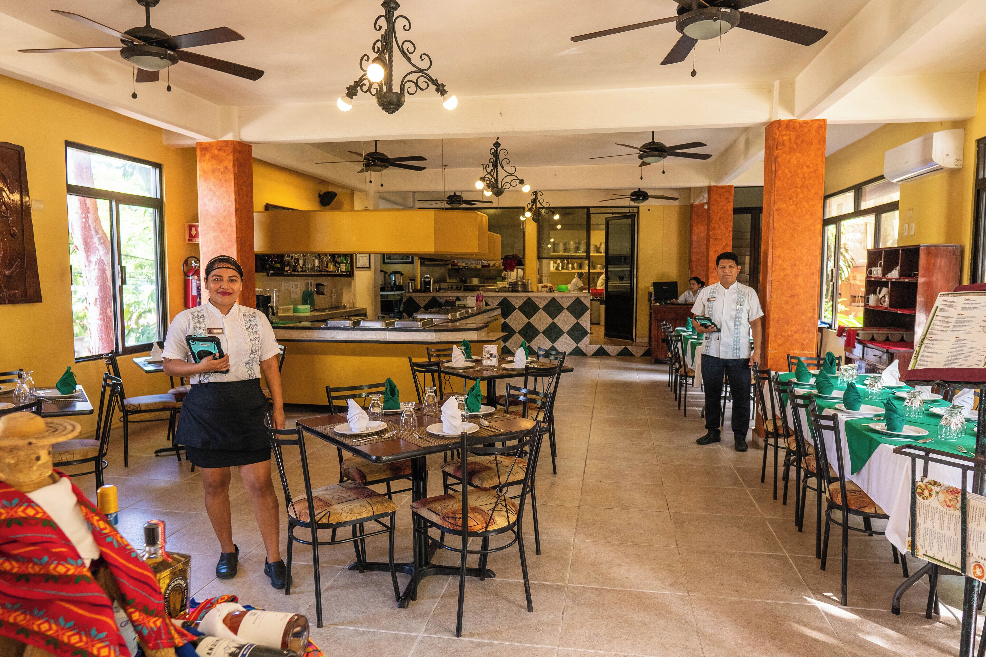 Un restaurant doté de nombreuses tables, de ventilateurs de plafond et d’un bar.