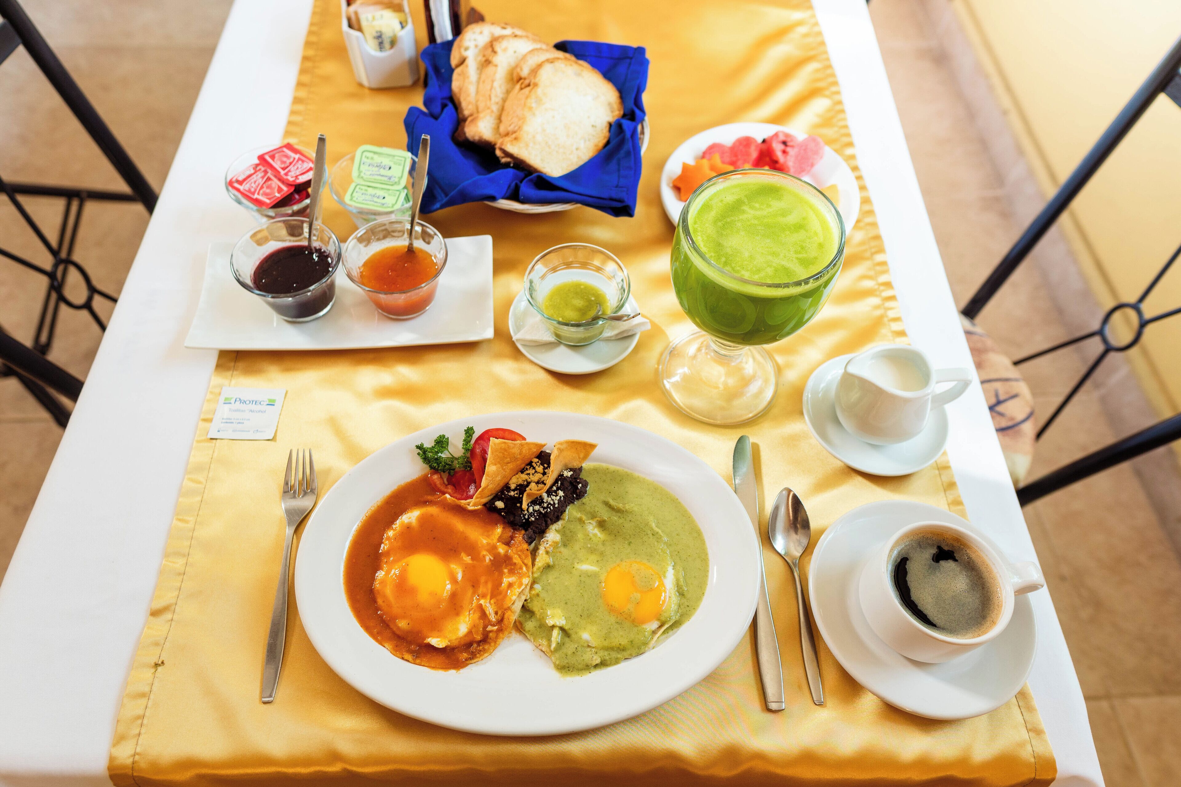 A breakfast table with a plate of eggs, toast, and a green smoothie.