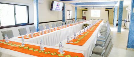 A conference room with a long table, chairs, and a TV screen.