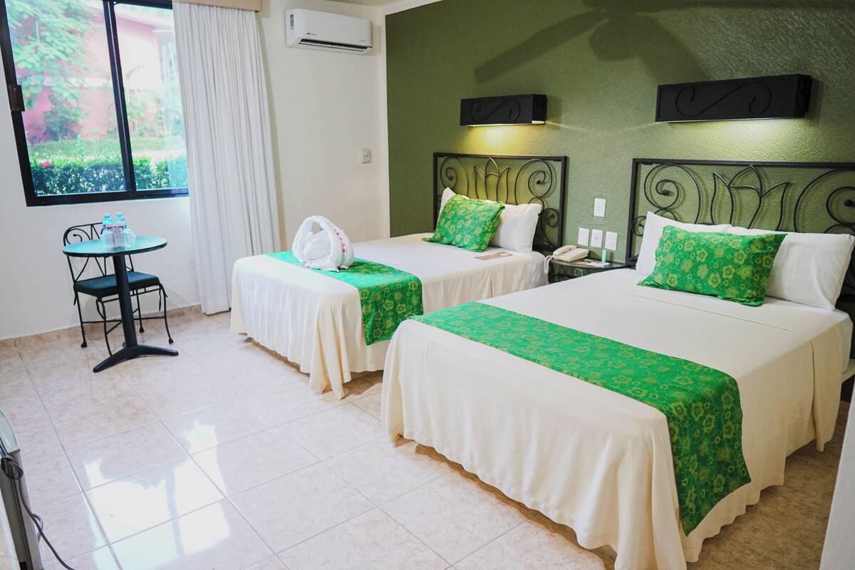 Una habitación de hotel con dos camas, una mesita pequeña y una silla.