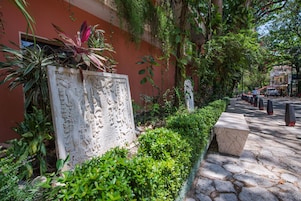 Un camino de piedra bordeado de vegetación y una losa decorativa con grabados.
