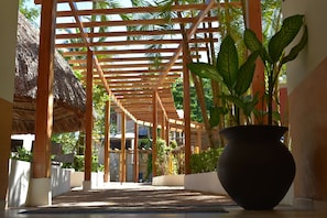 A covered walkway with wooden beams and a large potted plant. - Hotel Maya Tulipanes Palenque (Palenque)