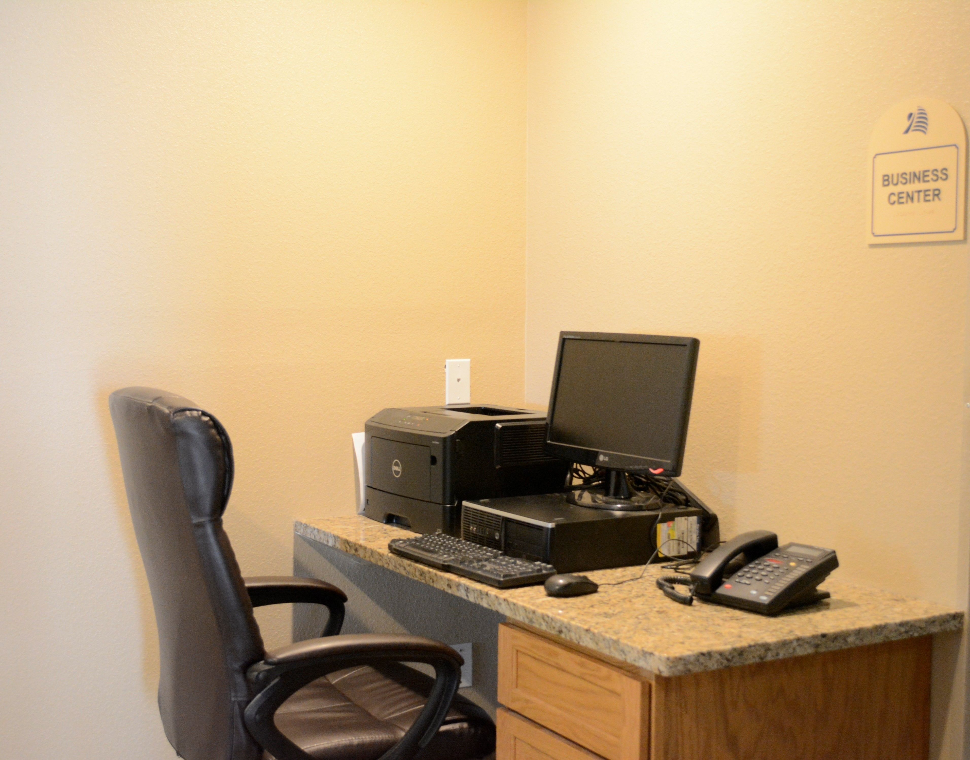 A business center with a desktop computer, printer, keyboard, mouse, and phone.