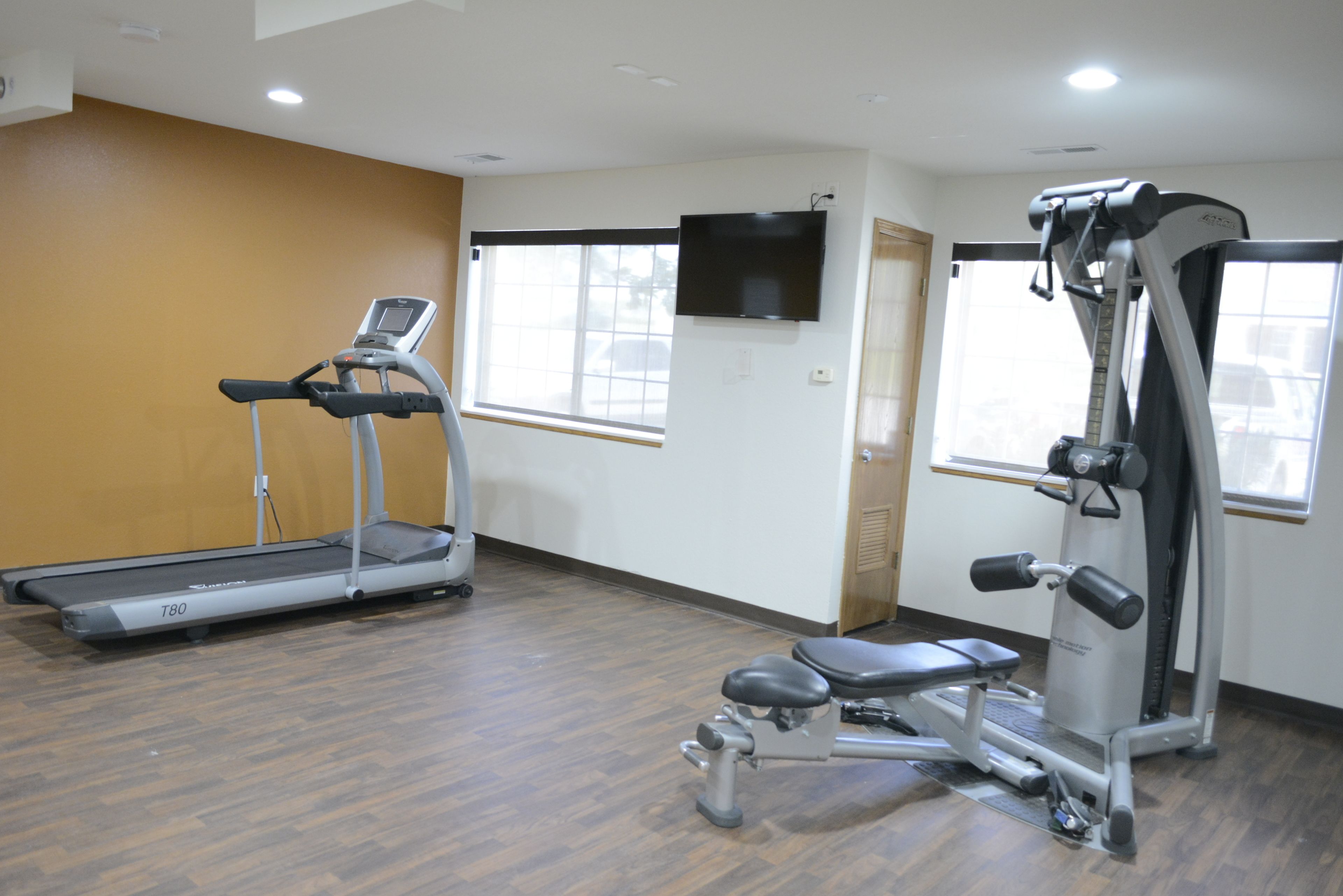A gym with a treadmill, weight bench, and exercise machine.