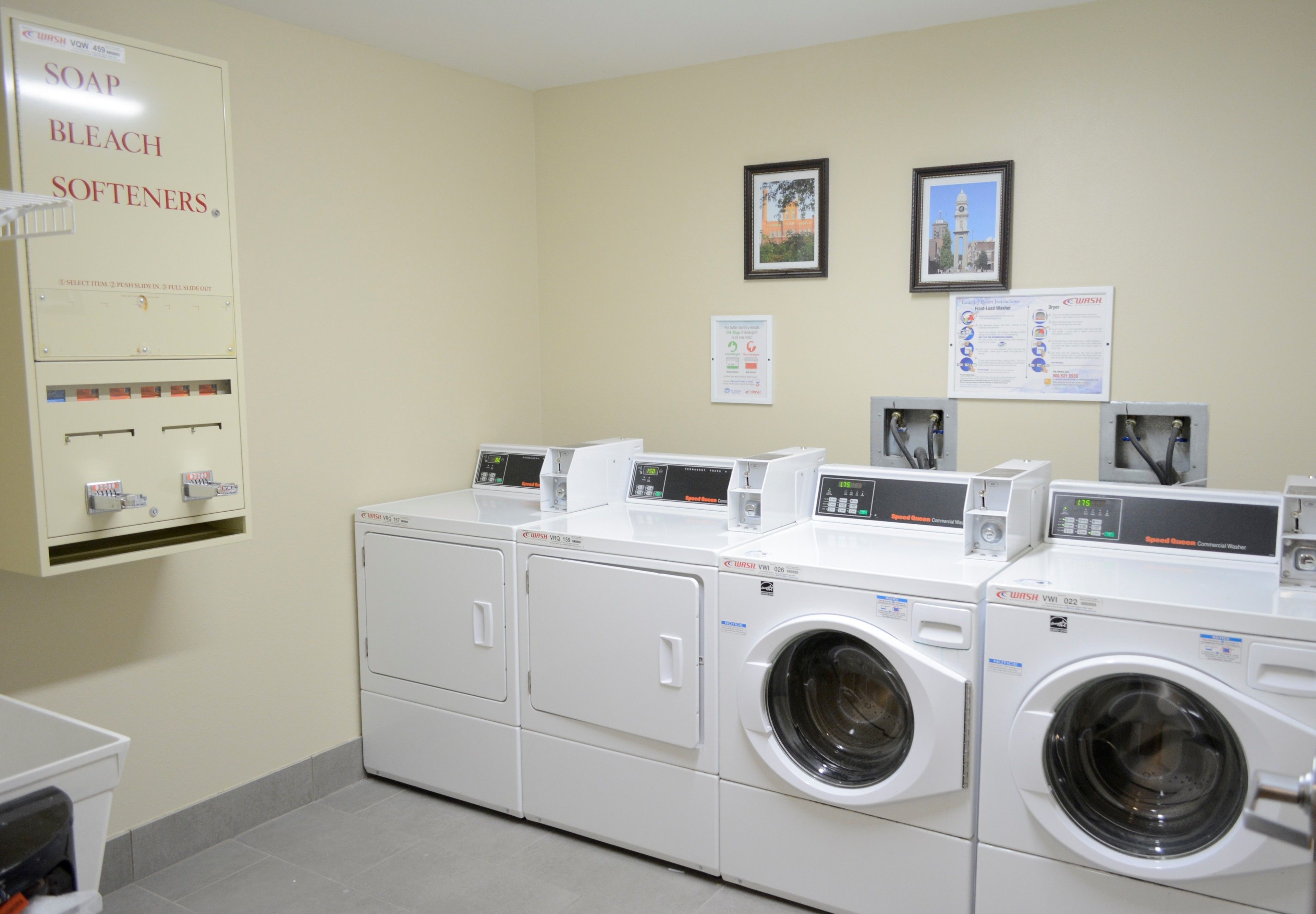 A laundry area with multiple washing machines and a soap and bleach softener dispenser.