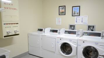 A laundry area with multiple washing machines and a soap and bleach softener dispenser.