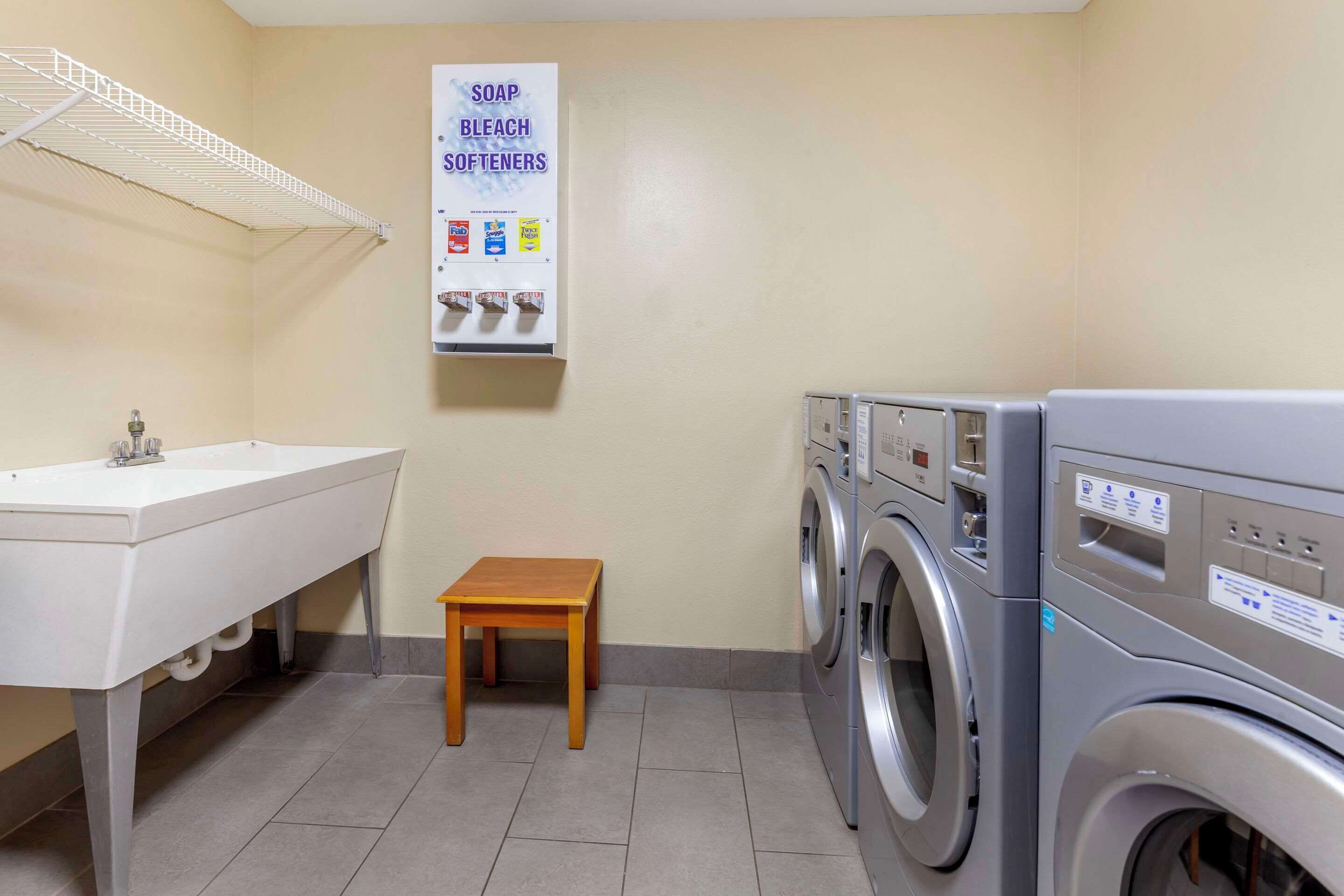 A laundry area with a washing machine, a sink, and a small table.
