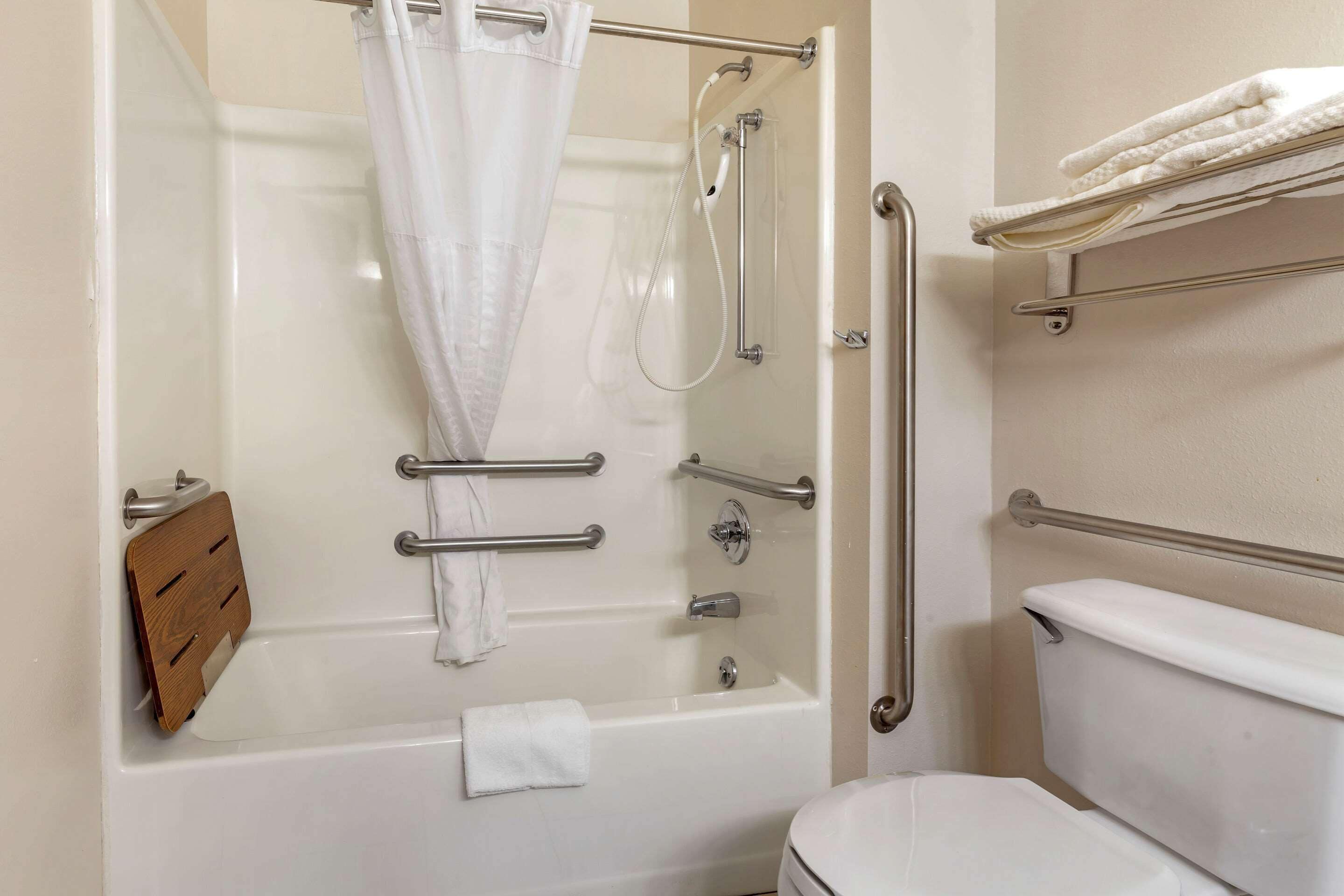A modern bathroom with a walk-in shower, grab bars, a toilet, and a towel rack.