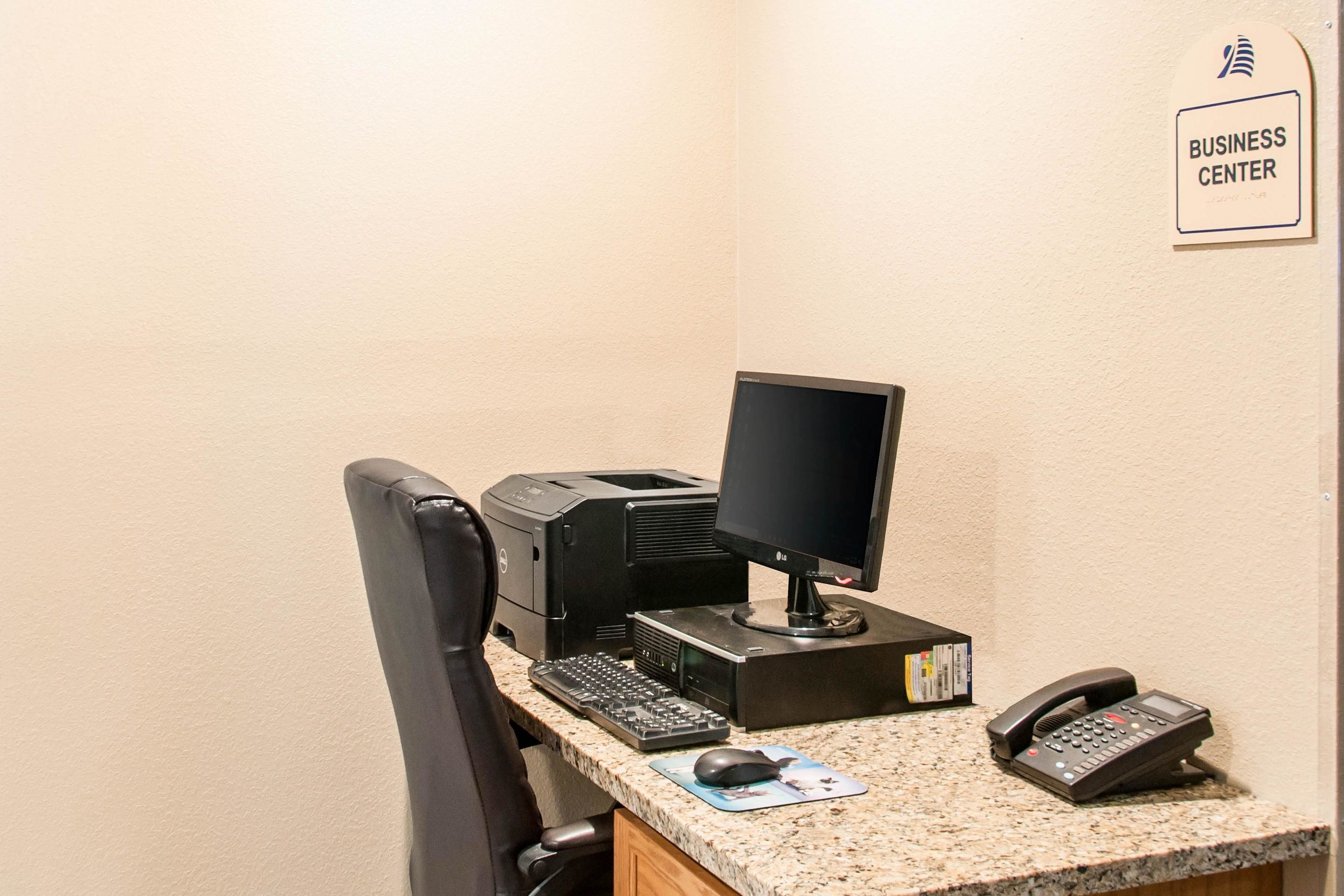 Un bureau dans un centre d’affaires, équipé d’un ordinateur de bureau, d’un écran, d’un clavier, d’une souris et d’un téléphone.