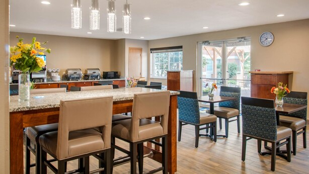 A modern kitchen with a marble countertop, stainless steel appliances, and hanging pendant lights. - MainStay Suites Dubuque at Hwy 20 (Dubuque)