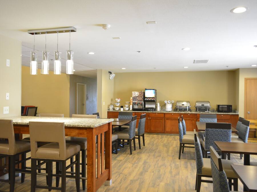 A hotel kitchen with a bar area, seating, and a coffee station.