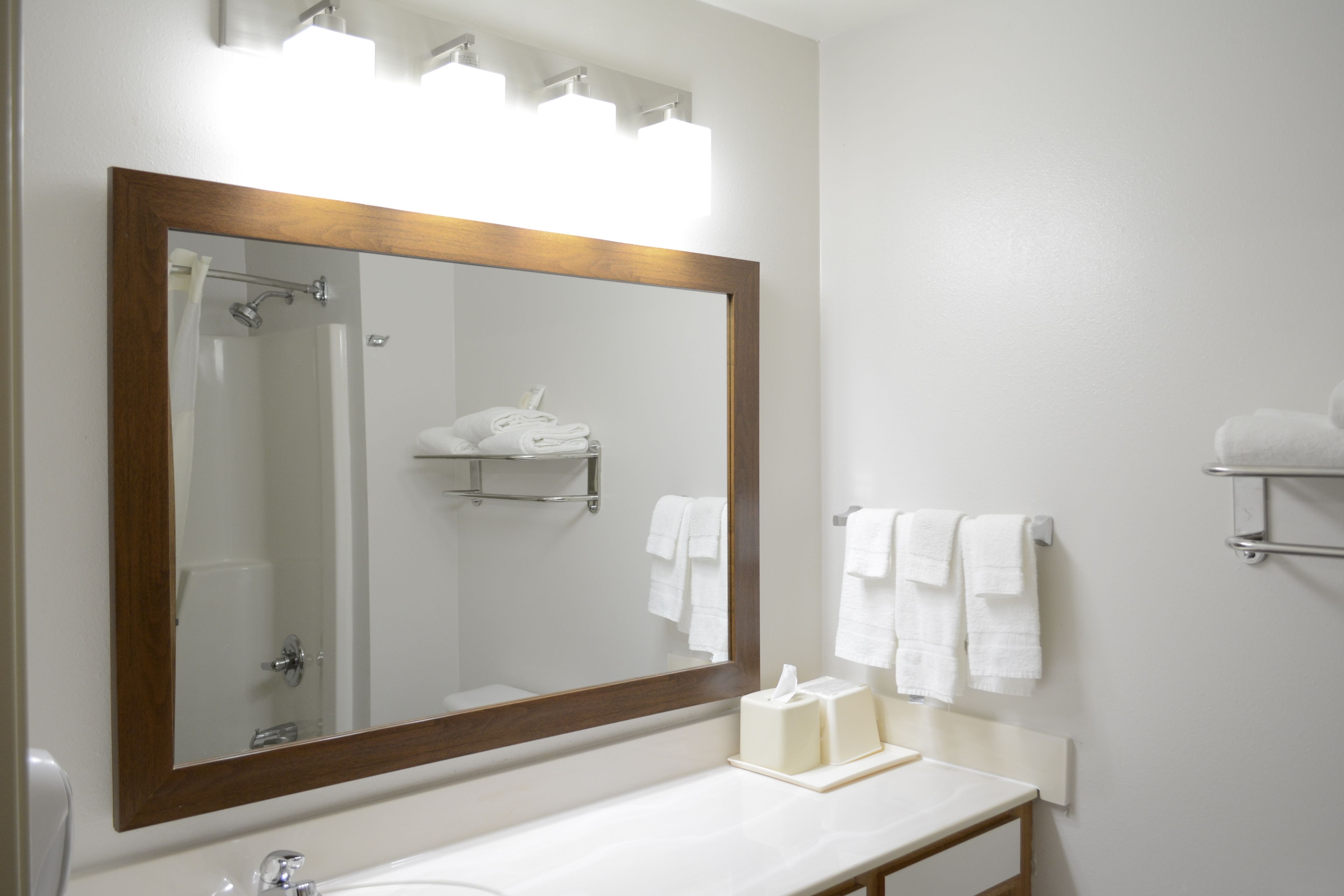 A bathroom with a large mirror, a white sink, and a towel rack.