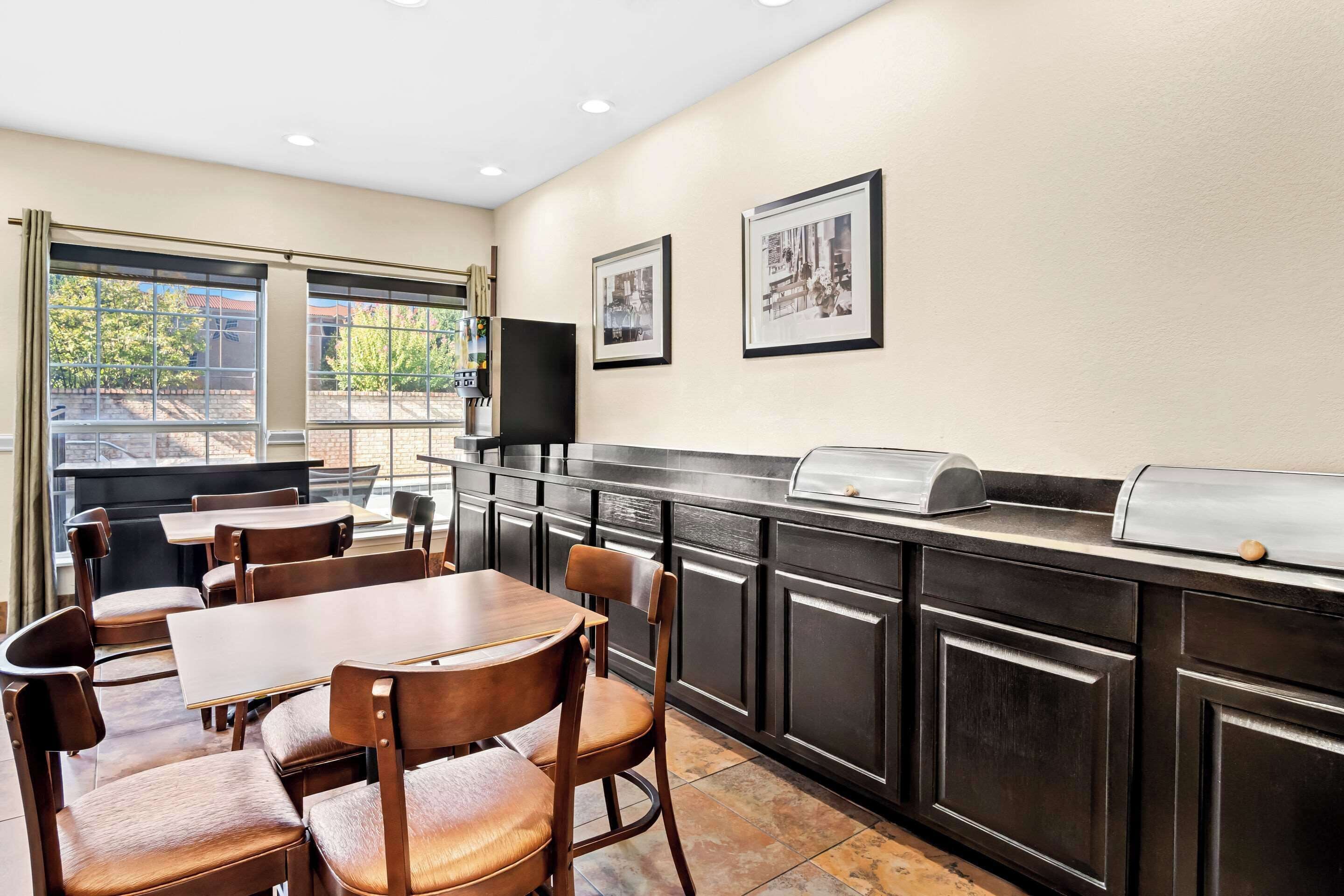A modern kitchen with a dining area, featuring a large window, dark cabinetry, and a built-in grill.