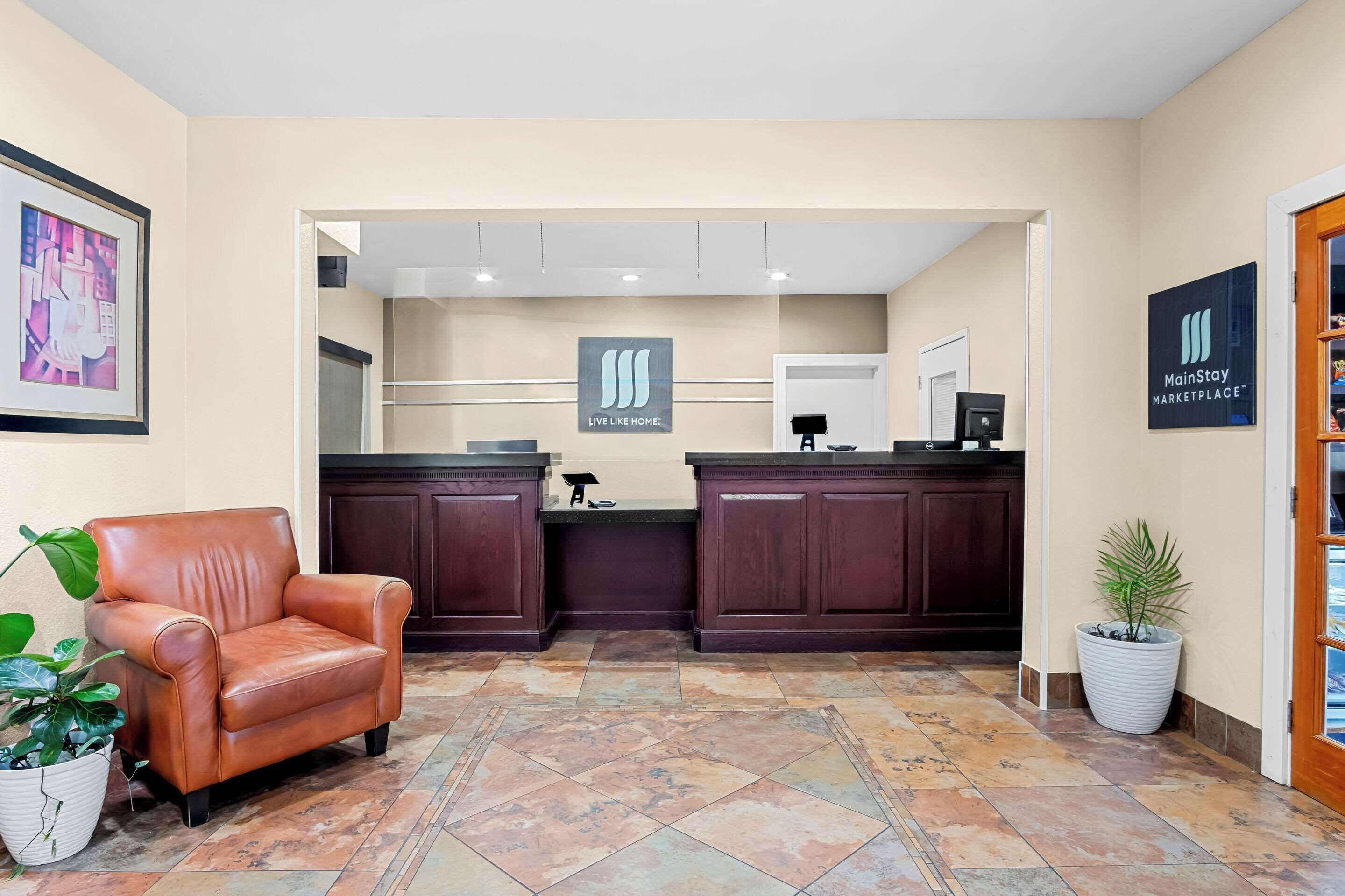 A reception area with a brown leather chair, a reception desk, and a potted plant.