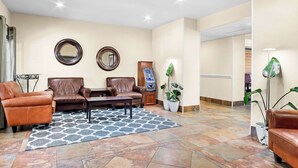 A lobby with leather sofas, a patterned rug, and a reception desk with a digital kiosk. - MainStay Suites Addison-Dallas (Addison)