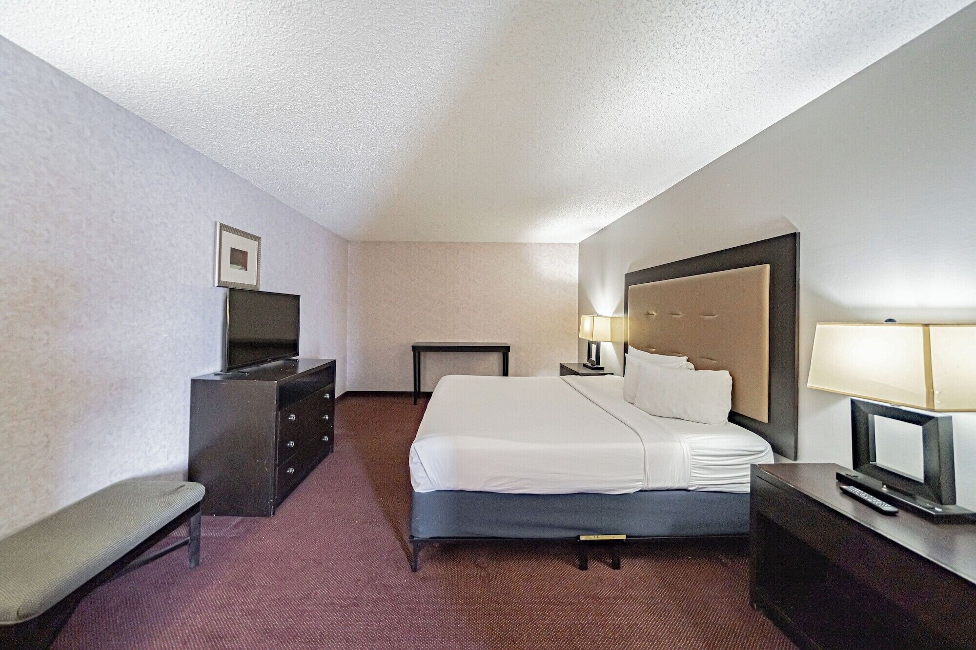 Une chambre d ’hôtel avec un lit, une télévision, un bureau et une chaise.