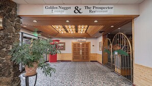 A lobby with a patterned carpet, a wooden ceiling, and a sign for Golden Nugget Lounge & The Prospector Restaurant.