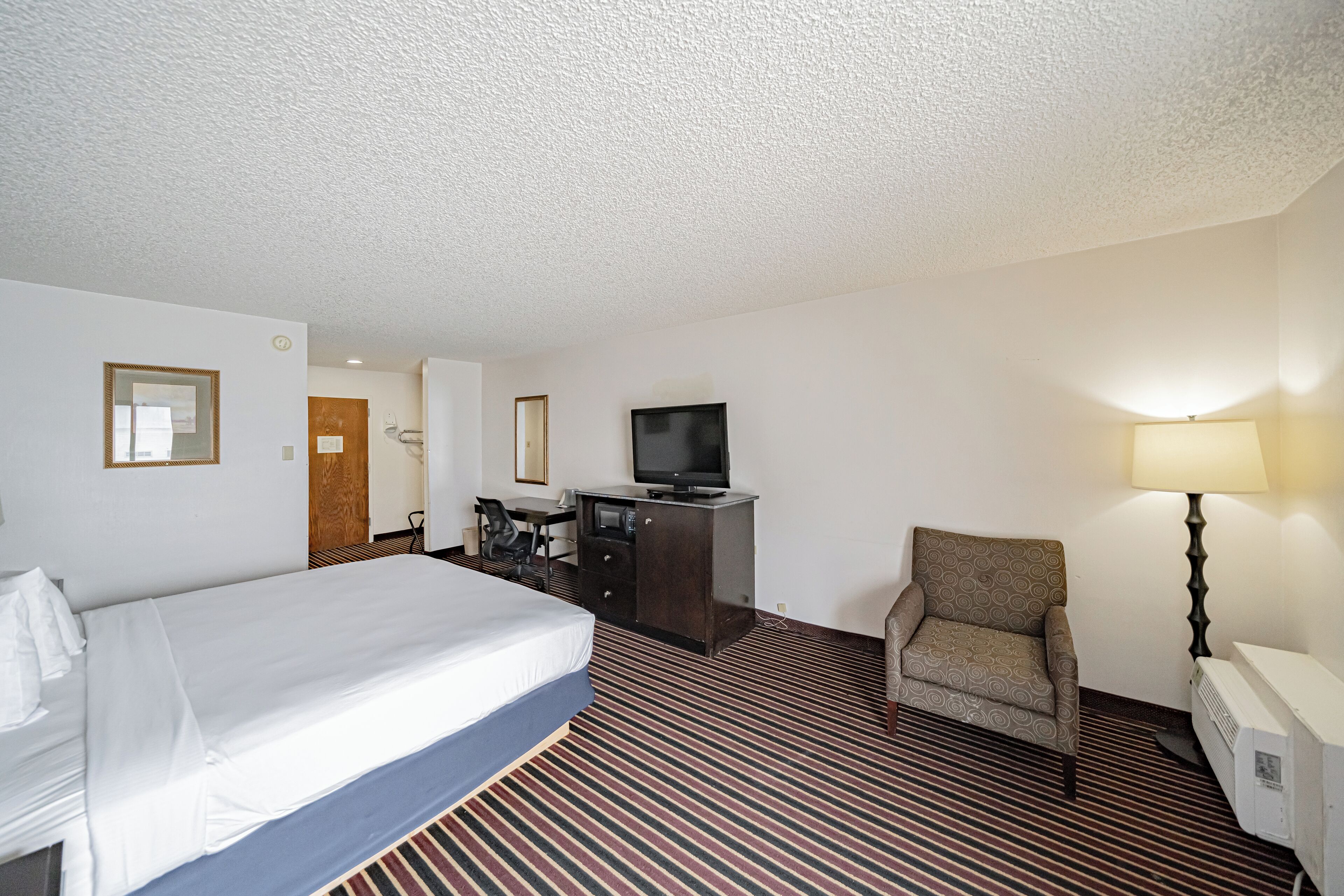 Une chambre d’hôtel équipée d’un lit, d’un bureau, d’une chaise, d’une télévision et d’une lampe.