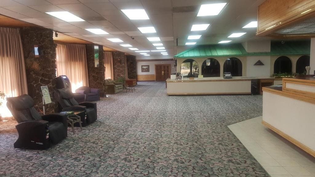 Un hall d’hôtel comprenant un comptoir d’accueil, un espace salon avec des fauteuils et un tapis à motifs.
