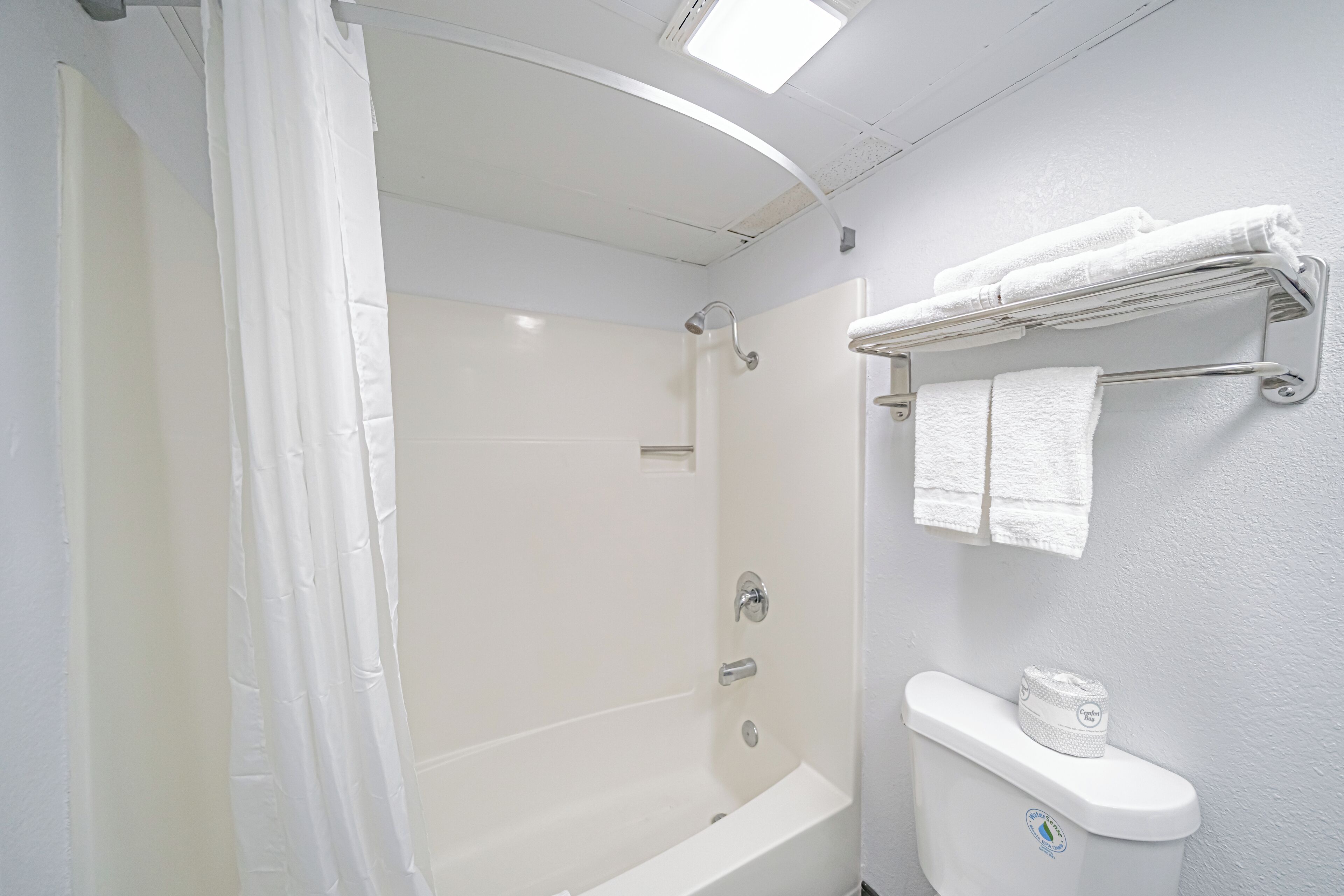 Un baño con bañera, inodoro y cortina de ducha.