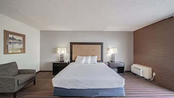A hotel room with a large bed, two bedside tables with lamps, a sofa, and a radiator.