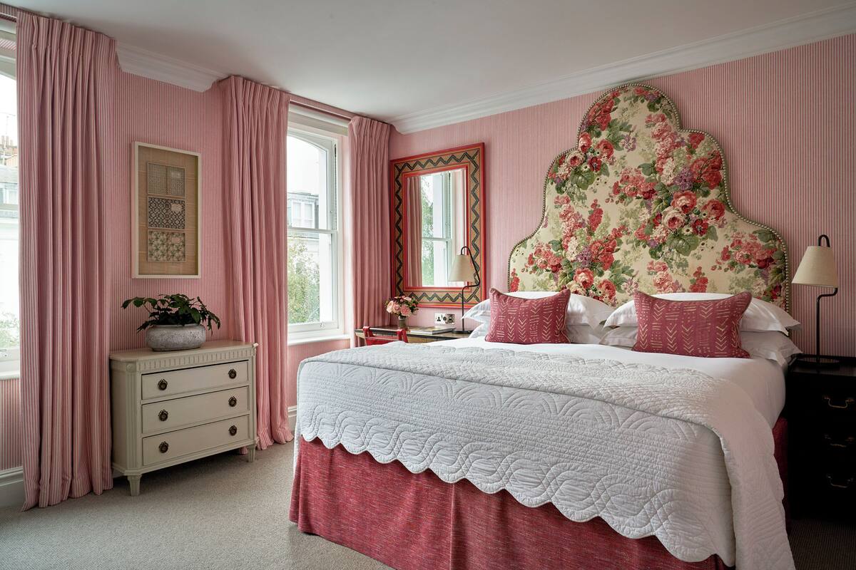 A bedroom with a bed, a dresser, a mirror, and a window with curtains.