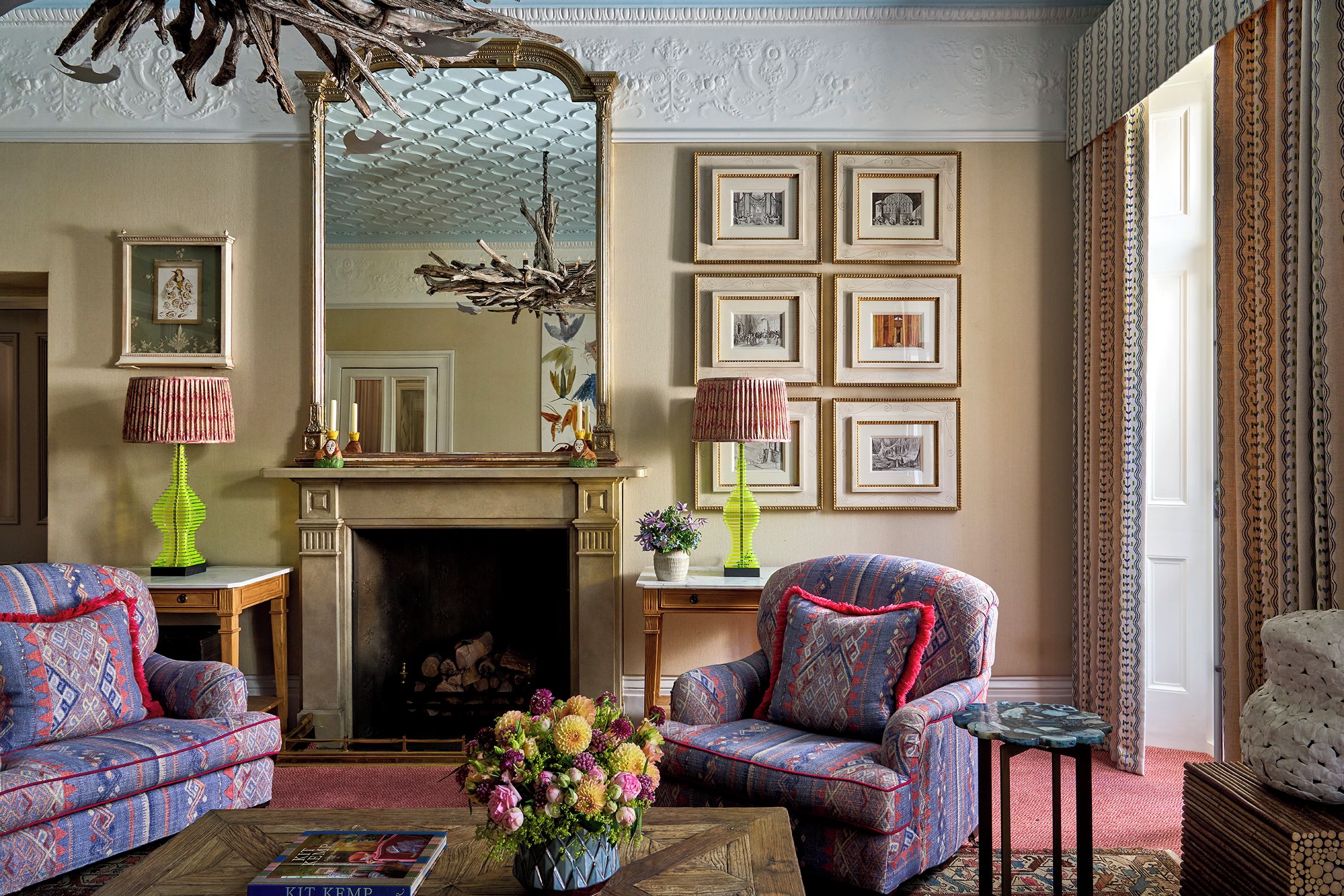 A traditional living room with patterned furniture, a fireplace, and framed artwork on the wall.
