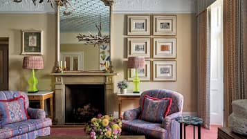 A traditional living room with patterned furniture, a fireplace, and framed artwork on the wall.