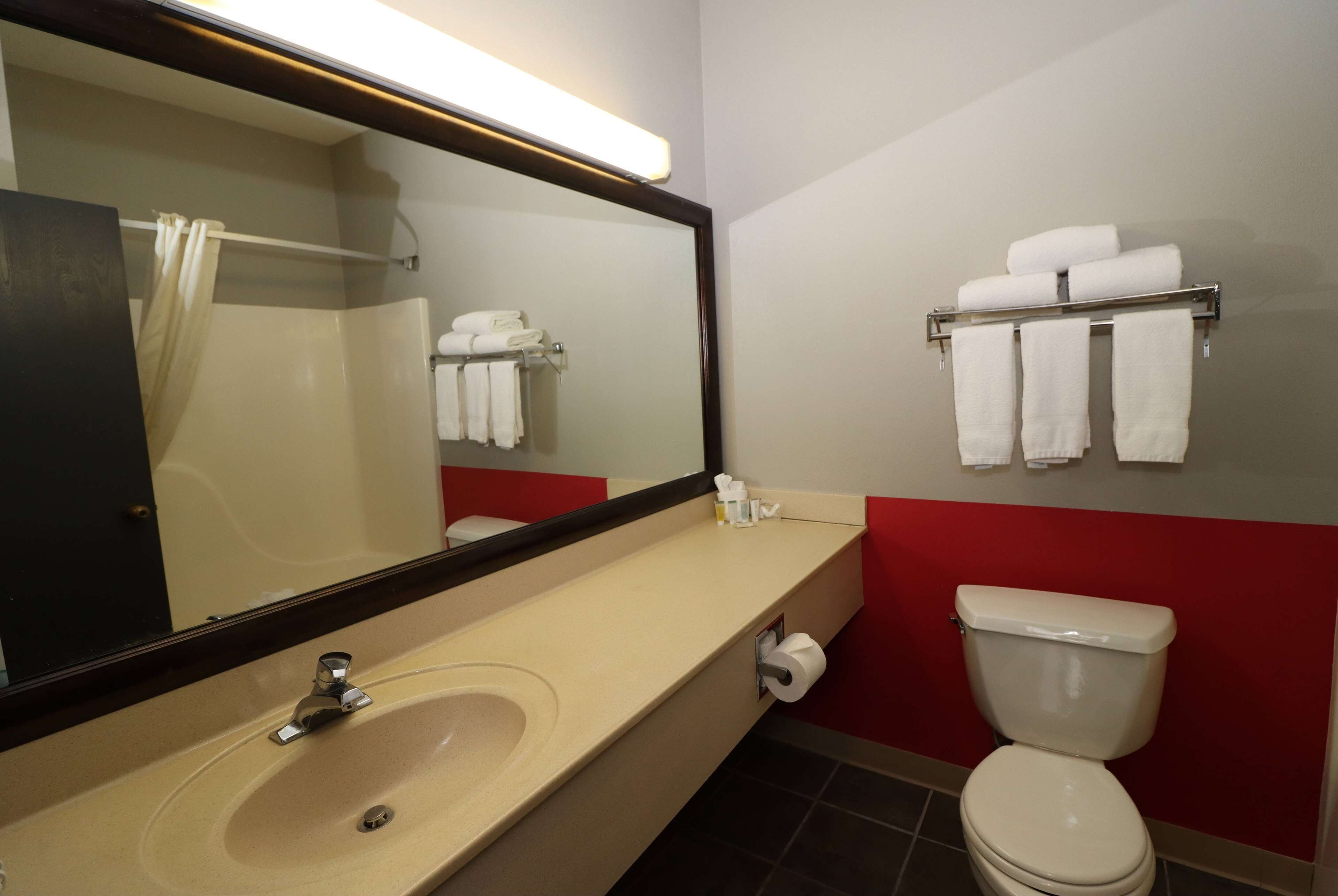 A bathroom with a sink, mirror, towel rack, and toilet.