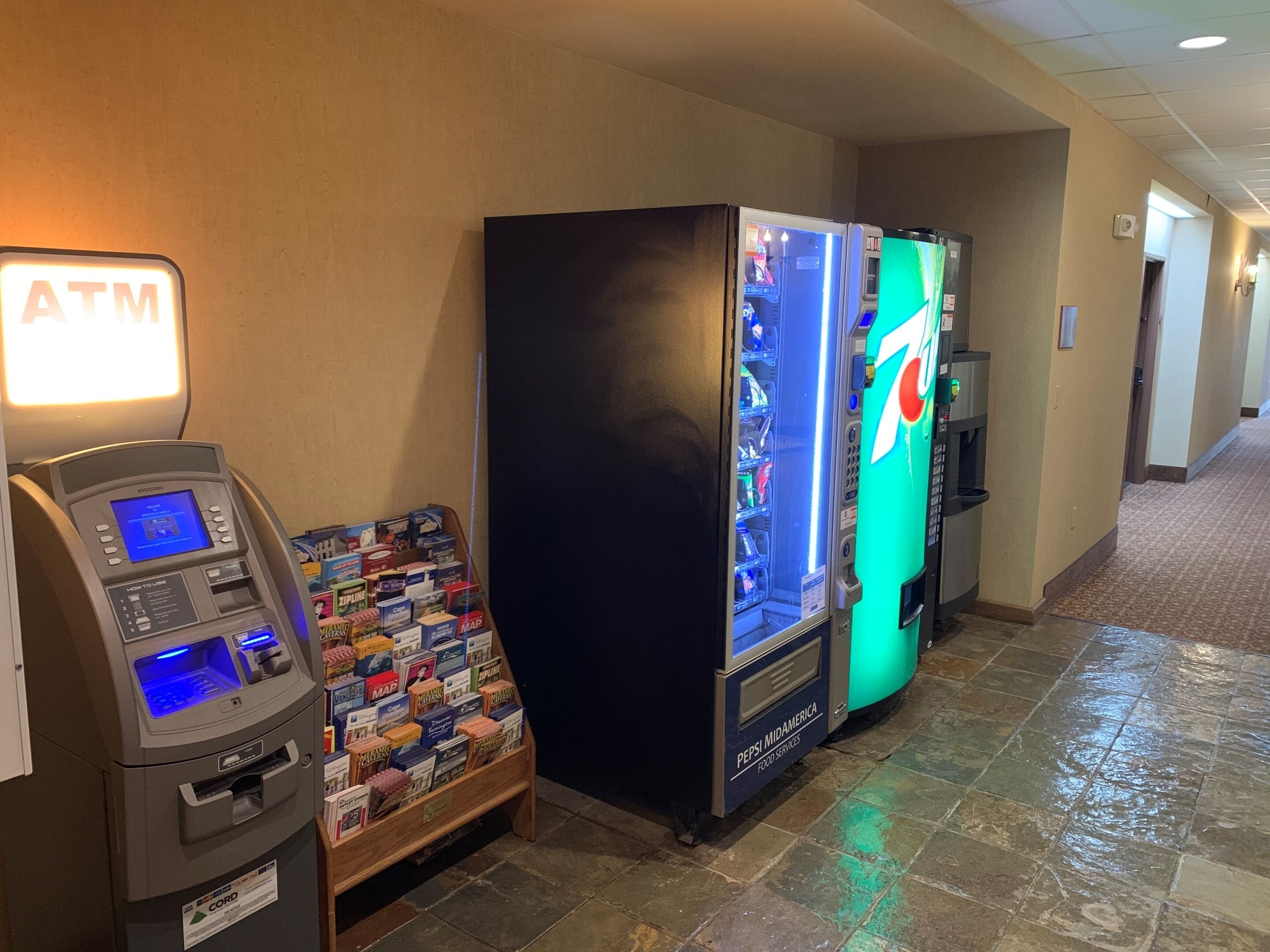 Een pinautomaat, een automaat en een 7-Eleven in een hotelgang.