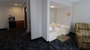 Une chambre d’hôtel équipée d’une kitchenette, d’un grand miroir, d’un canapé et d’un tapis à motifs.