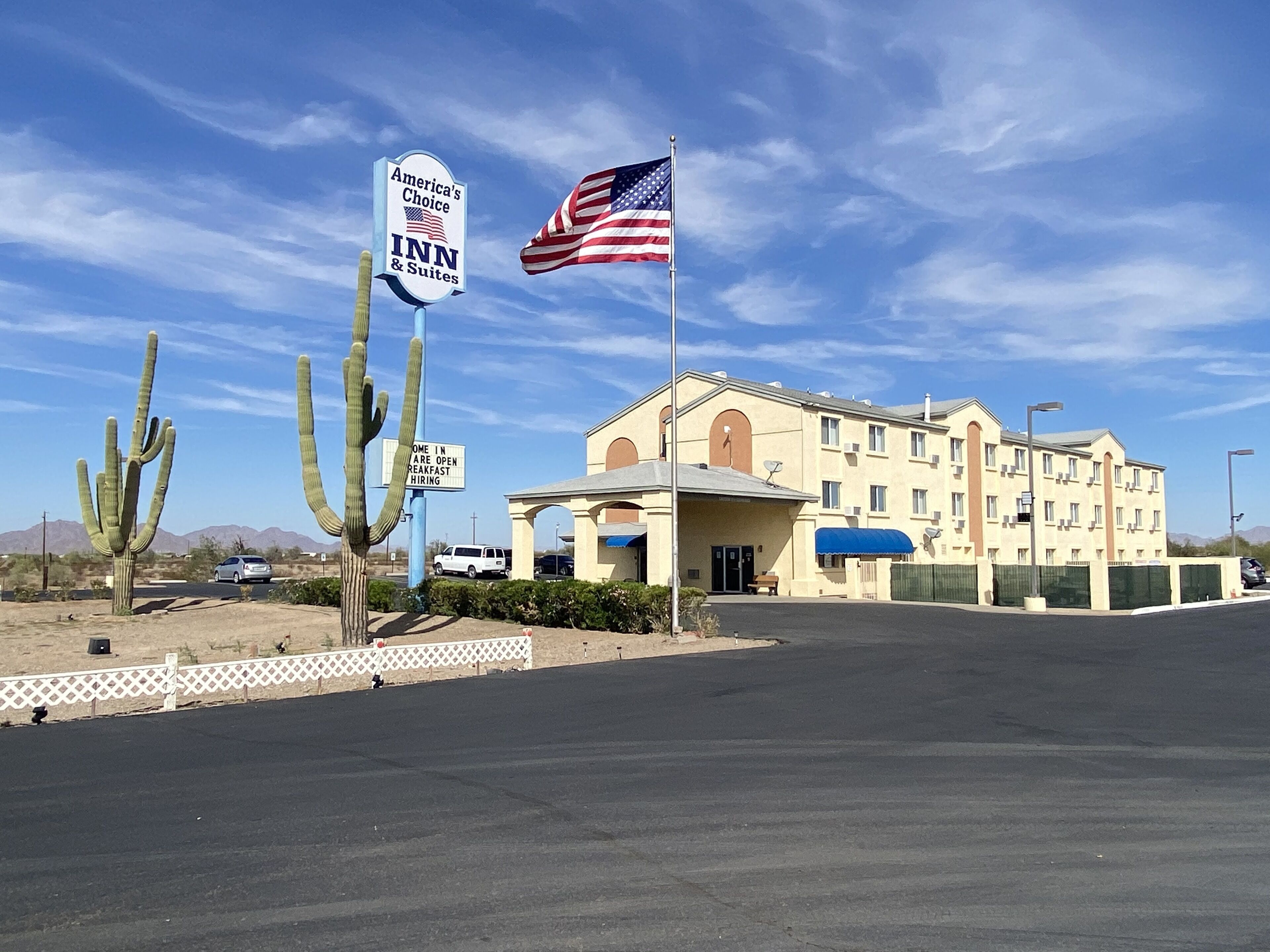 Un edificio con un letrero que dice America's Choice INN & Suites, una bandera y un paisaje desértico.