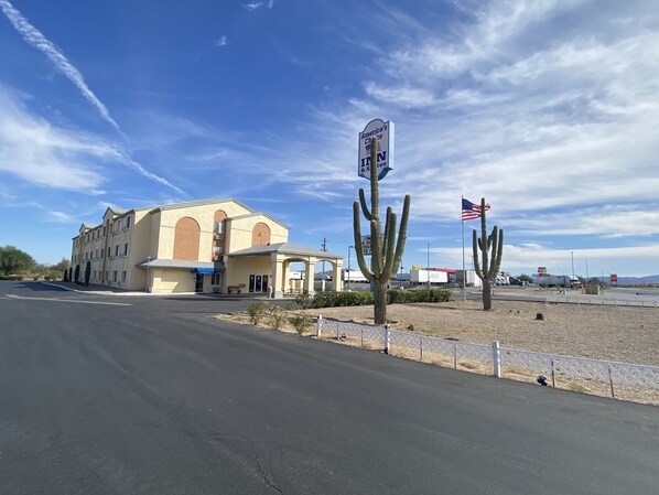 A building with a sign reading "America's Choice Inn & Suites" and a large cactus in front.