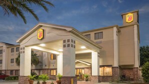 A hotel with a covered entrance, potted plants, and a brick facade. - Super 8 by Wyndham Duson Lafayette West Area (Duson)
