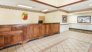 A reception area with a wooden reception desk, a clock, and a framed picture on the wall. - Super 8 by Wyndham Duson Lafayette West Area (Duson)