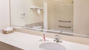 A bathroom with a large mirror, a sink, a towel rack, and a shower door.
