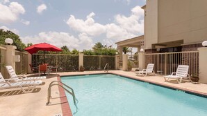 A swimming pool with lounge chairs and a red umbrella. - Super 8 by Wyndham Duson Lafayette West Area (Duson)