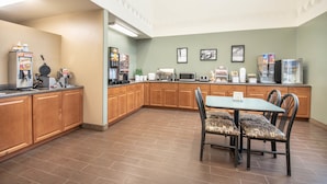 A kitchen with wooden cabinets, a microwave, a coffee maker, and a dining table with chairs. - Four Seasons Inn (Bottineau)