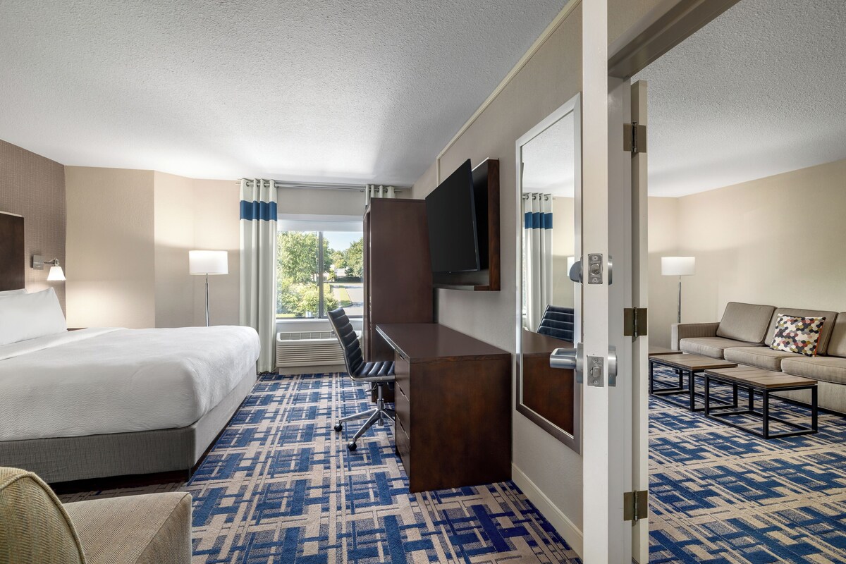 Een hotelkamer met een bed, bureau, stoel, bank en televisie.