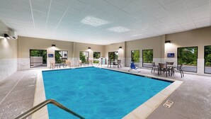 Une grande piscine intérieure à l’eau d’un bleu limpide, entourée d’espaces de repos et de fenêtres sur lesquelles on peut lire la mention « Il est interdit de plonger ».