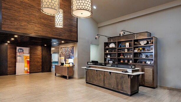 Un hall d’entrée moderne avec des panneaux de bois, un comptoir de réception et une étagère décorative où sont exposés divers objets.