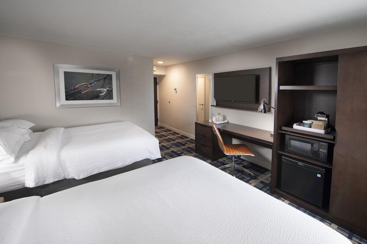 Hotelkamer met twee bedden, een bureau met stoel, een televisie, een magnetron en een kleine koelkast.
