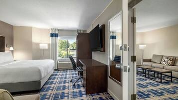 A hotel room with a bed, desk, TV, and a sofa.