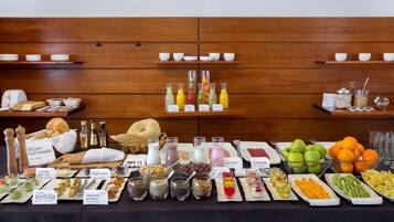 A buffet with various food and drink options, including fruits, vegetables, and beverages.