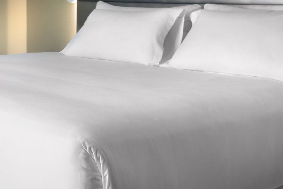 Una cama bien hecha con sábanas blancas y un cabecero.