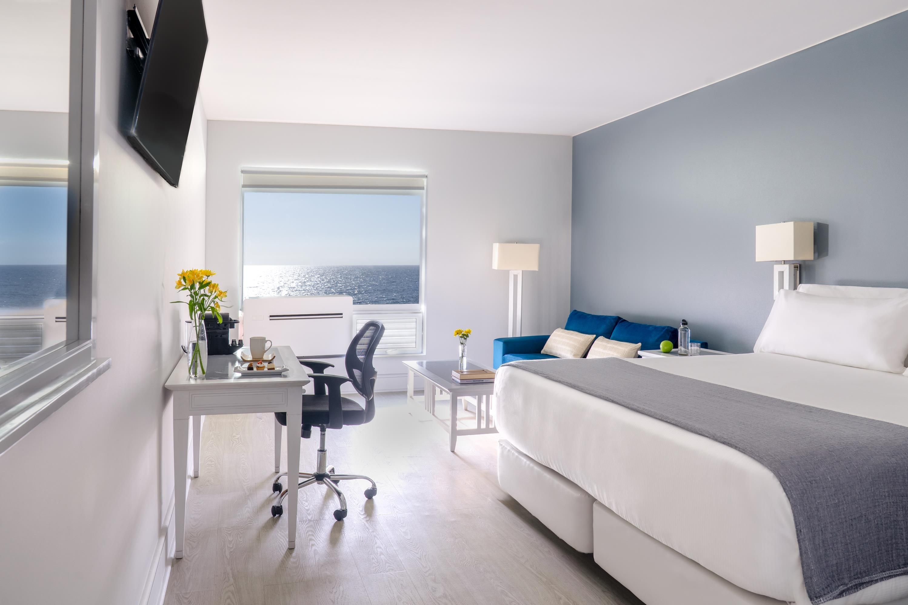 Una habitación de hotel con cama, escritorio, silla y vista al mar.