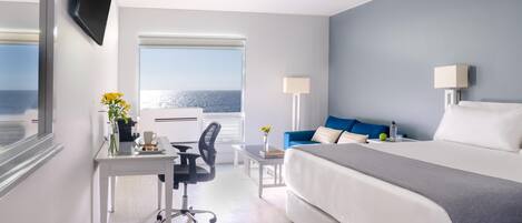 Una habitación de hotel con cama, escritorio, silla y vista al mar.