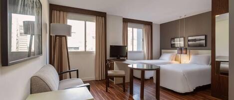 Una habitación de hotel con cama, sofá, escritorio, televisión y ventana con cortinas.