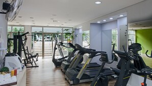 Une salle de sport moderne  équipée de plusieurs tapis de course, d’un vélo d’appartement et d’un rameur.