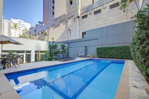 Una piscina al aire libre de temporada, sombrillas